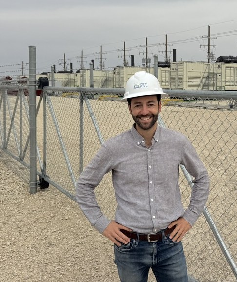 Alex Shoer in a hard hat outside the fence of a customer's power generation site
