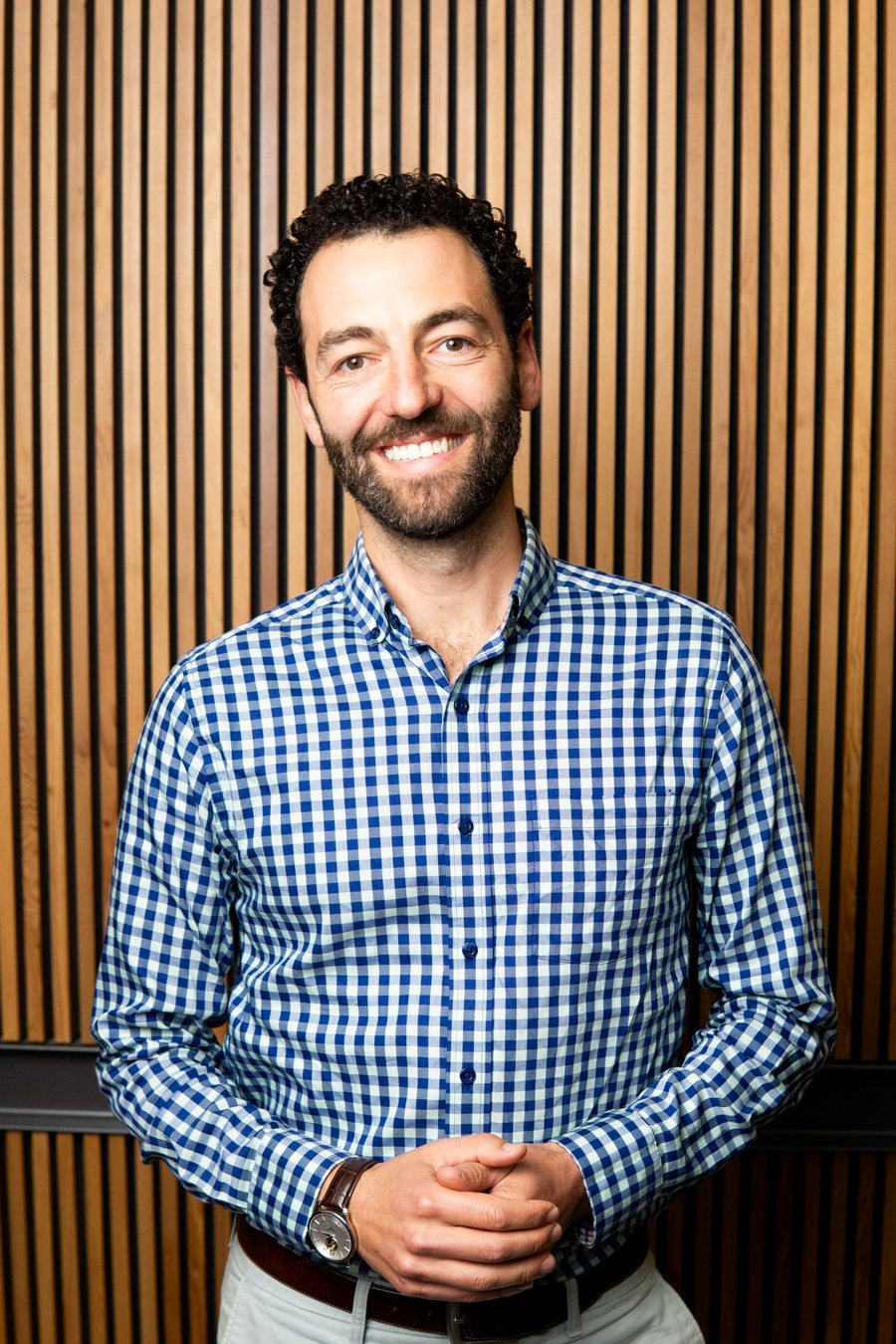 Alex Shoer standing in front of a wood-slat wall